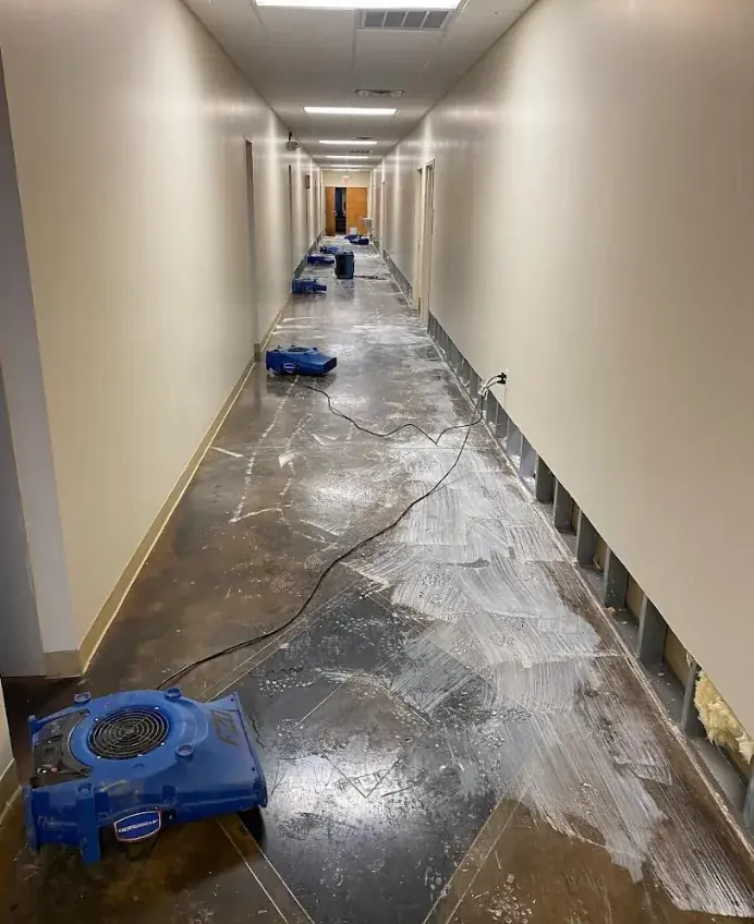 Long apartment corridor lined with air movers drying the floor at an Atlanta building